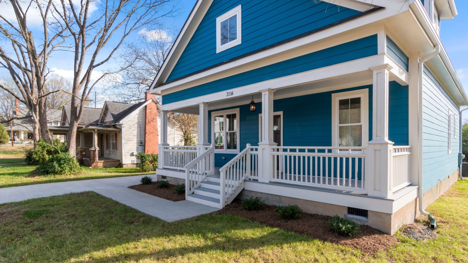 Blue craftsman-style home with white front porch on a sunny day — Encore Enclosures & Windows serves Louisville and Southern Indiana